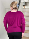 Woman standing with her back towards the camera showing the back of Miik's Kallyn slouchy dolman long sleeve top in ruby