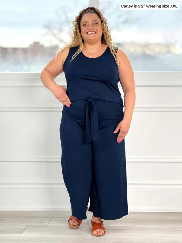 Miik model Carley (five feet two, size double extra large) smiling wearing Miik's Kimmay open-back capri jumpsuit in navy