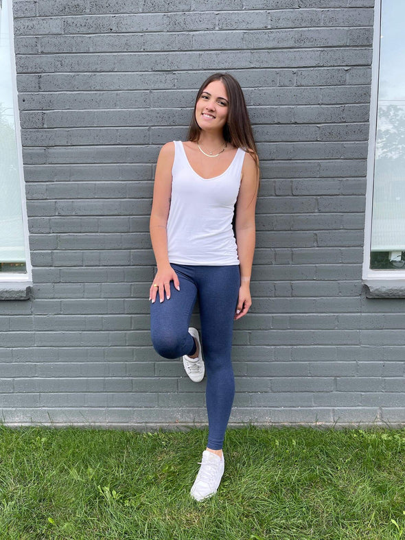 Woman leaning against to a brick wall smiling wearing  Miik's Lisa2 colourful high waisted legging in navy melange with a white tank top
