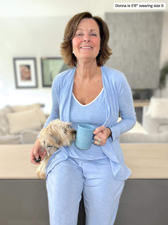 Woman smiling standing in a living room wearing Miik's Lori reversible slouchy tank top in denim melange with a matching colour cardigan and pants