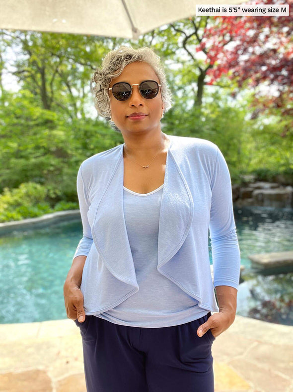 Woman standing next to a pool wearing Miik's Lori reversible slouchy tank top in denim melange with a matching colour cropped cardigan and a  navy pant