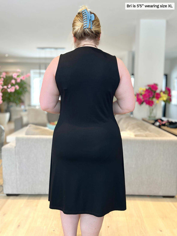 Woman standing with her back towards the camera showing the back of Miik's Mary Jo sleeveless v-neck dress in black