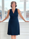 Woman smiling standing in front of a window/white wall wearing Miik's Mary Jo sleeveless v-neck dress in navy