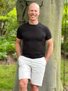 Man leaning on a tree wearing Miik's Mick square neck t-shirt in black with white shorts.