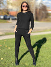 Woman standing on grass wearing Miik's Jamie round neck long-sleeve in black with black joggers.