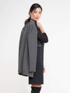 Woman standing wearing Miik's Nadia asymmetric seam dress in black with a grey blazer over her shoulder.