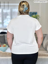 Woman standing with her back towards the camera showing the back of Miik's Noah draped dolman top in white