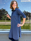 Woman standing in front of a window looking up wearing Miik's Rafaela dressy collared tunic top in navy melange with a navy legging 