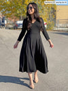 Woman smiling while looking away wearing Miik's Rebel midi flounce dresss with pockets in black with high heels and sunglasses 