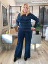 Woman standing in her office wearing Miik's Reed high waisted pant with pockets in navy with a long sleeve top in navy wide pinstripe