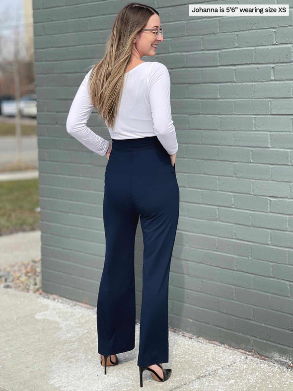 Woman standing with her back towards the camera showing the back of Miik's Reed high waisted pant with pockets