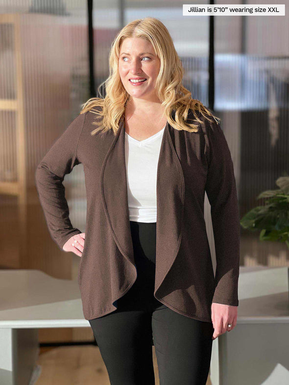Woman standing in a office room wearing Miik's Rory waterfall cardigan in chocolate melange with a white top and black pant  