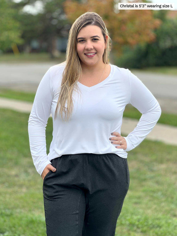 Woman standing outside wearing Miik's Sarvi v-neck long sleeve top in white with charcoal pants