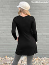Woman standing with her back towards the camera showing the back of Miik's Saya tunic with pockets in black with a granite legging