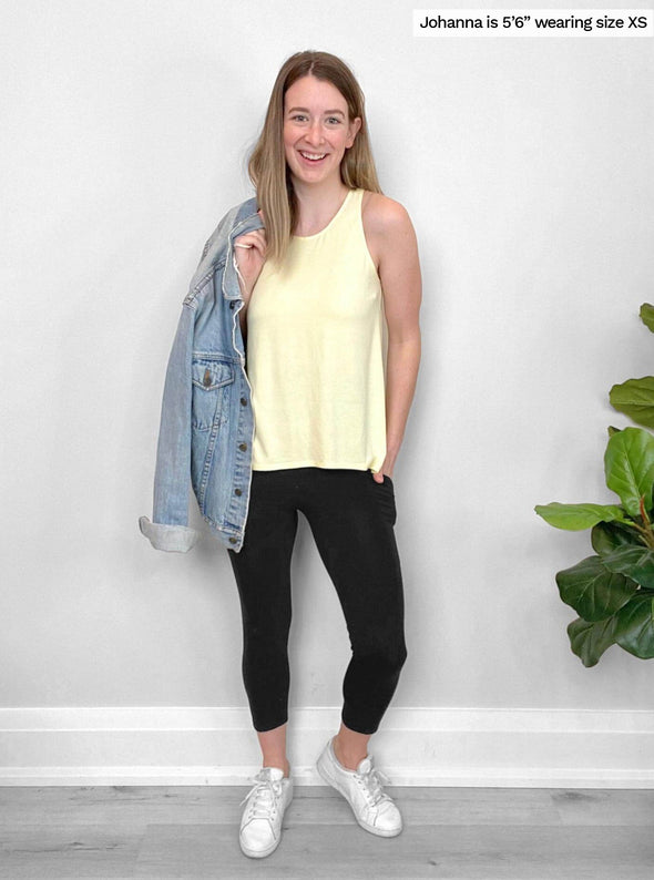 Woman standing in front of a wall wearing Miik's Seana high waisted pocket capri legging in black with a yellow top and jean jackets.