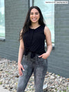 Woman standing in front of a grey wall laughing wearing Miik's Shane reversible button-up top in black with grey jeans.