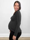 Pregnant woman standing sideway in front of a white wall wearing Miik's Shannon long sleeve reversible tee in charcoal with legging in black