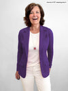 Woman standing in front of a white wall laughing while wearing Miik's Sienna girlfriend blazer in purple colour.