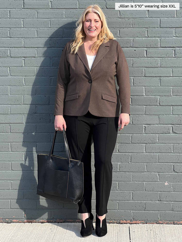 Woman smiling standing in front of a brick wall wearing Miik's Sienna girlfriend blazer in chocolate melange closed and black pants