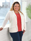 Miik model Carley (five feet two, size double extra large) smiling in front of a window wearing a striped top in papaya, navy pant and Miik's Sienna girlfriend blazer in natural