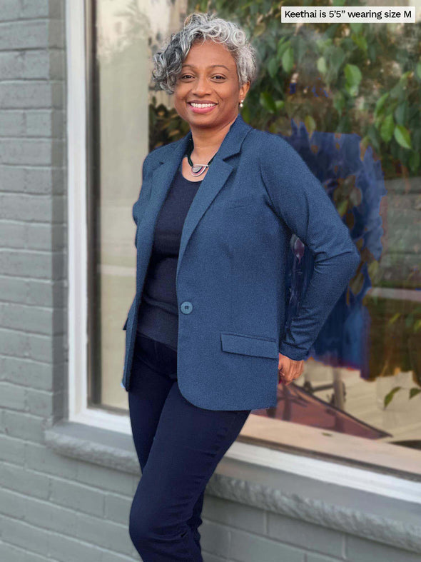 Miik model Keethai leaning against a window outside while wearing the Sienna blazer in navy melange.