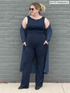 Woman standing in front of a brick wall wearing an all navy outfit: Miik's Sierra pocket pant, Liam top and Shevan long cardigan