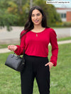Woman smiling and looking away wearing Miik's Silvie slouch pant in black with a long sleeve top in red wine