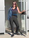 Woman opening the door wearing Miik's Silvie slouch pant in grey with grey purple and blue stripe top.