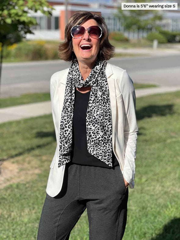 Woman laughing wearing Miik's Silvie slouch pant in charcoal along with an animal print scarf, black top and a blazer in natural