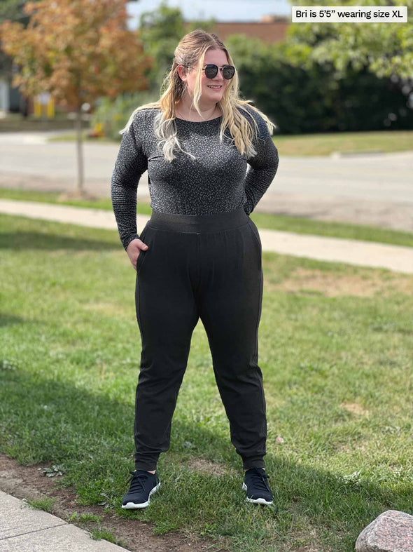 Woman smiling looking away wearing Miik's Silvie slouch pant in charcoal along with a long sleeve top in charcoal leopard print
