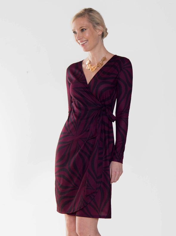 Model standing in front of a white wall sideway wearing Miik's Sonya wrap dress in geo print
