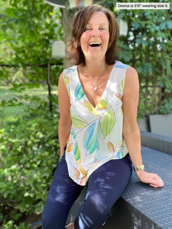 Woman laughing wearing Miik's Taz sleeveless inverted pleat top in tropical leaf print with jeans