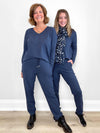 Two women standing in front of white wall wearing Miik's Tula long sleeve open-back jumpsuit in navy melange