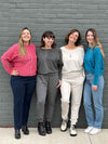 Four women standing in front of a brick wall all wearing all the different colours of Miik's Tully reversible fleece dolman sweater: oatmeal, teal melange, granite and pomegranate melange.