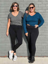 Two women standing in front of a brick wall wearing Miik's Tyson fleece legging in black along with a granite tee and a teal long sleeve top
