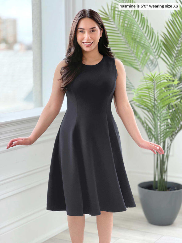 Miik model Yasmine (five feet tall, size extra small, petite) smiling wearing Miik's Valerie sleeveless fit and flare dress in graphite