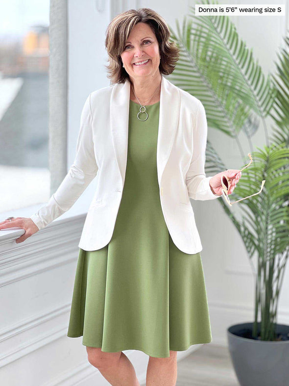 Miik founder Donna (five feet six, size small) smiling while wearing Miik's Valerie sleeveless fit and flare dress in green moss with a natural blazer 
