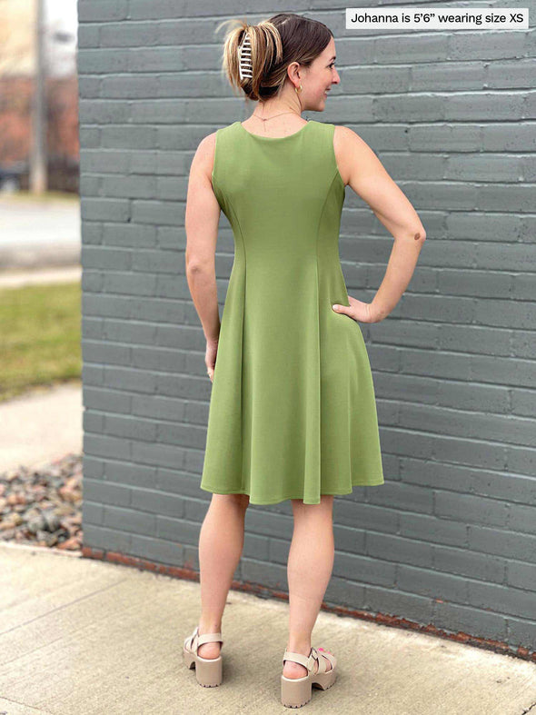 Miik model Johanna (five feet six, size extra small) standing with her back towards the camera showing the back of Miik's Valerie sleeveless fit and flare dress in green