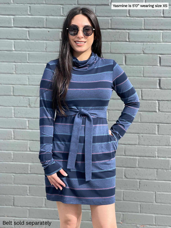 Woman smiling in front of a brick wall wearing Miik's Venice cowl pocket tunic in navy jewel tone stripe belted with a navy melange Blair belt and sunglasses