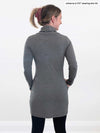 A woman standing with her back towards the camera wearing Miik's Vienna cowl neck pocket tunic in granite grey with black leggings.