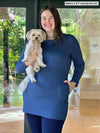 Woman smiling and holding a dog wearing a navy legging along with Miik's Vienna cowl pocket tunic in navy melange