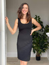 Woman standing in front of a wall wearing Miik's Yara reversible boat/scoopneck dress in black.