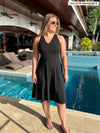 Woman standing in front of a pool looking away wearing Miik's Zayd v-neck racerback dress in black with sunglasses and flip flops