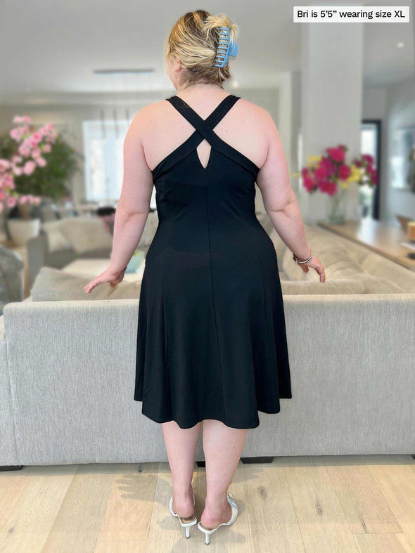 Woman standing with her back towards the camera showing the back of Miik's Zayd v-neck racerback dress in black 