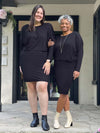 Two women standing in front of a door wearing Miik's Bali batwing sleeve dress in black.