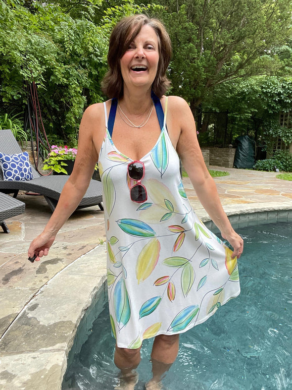 Woman standing in the pool wearing Miik's Astrid spaghetti strap dress in green leaf pattern.