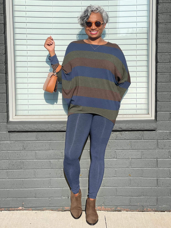 Woman smiling and standing in front of a window wearing Miik's Lisa2 colourful high waisted legging in a navy melange with a striped long sleeve  top